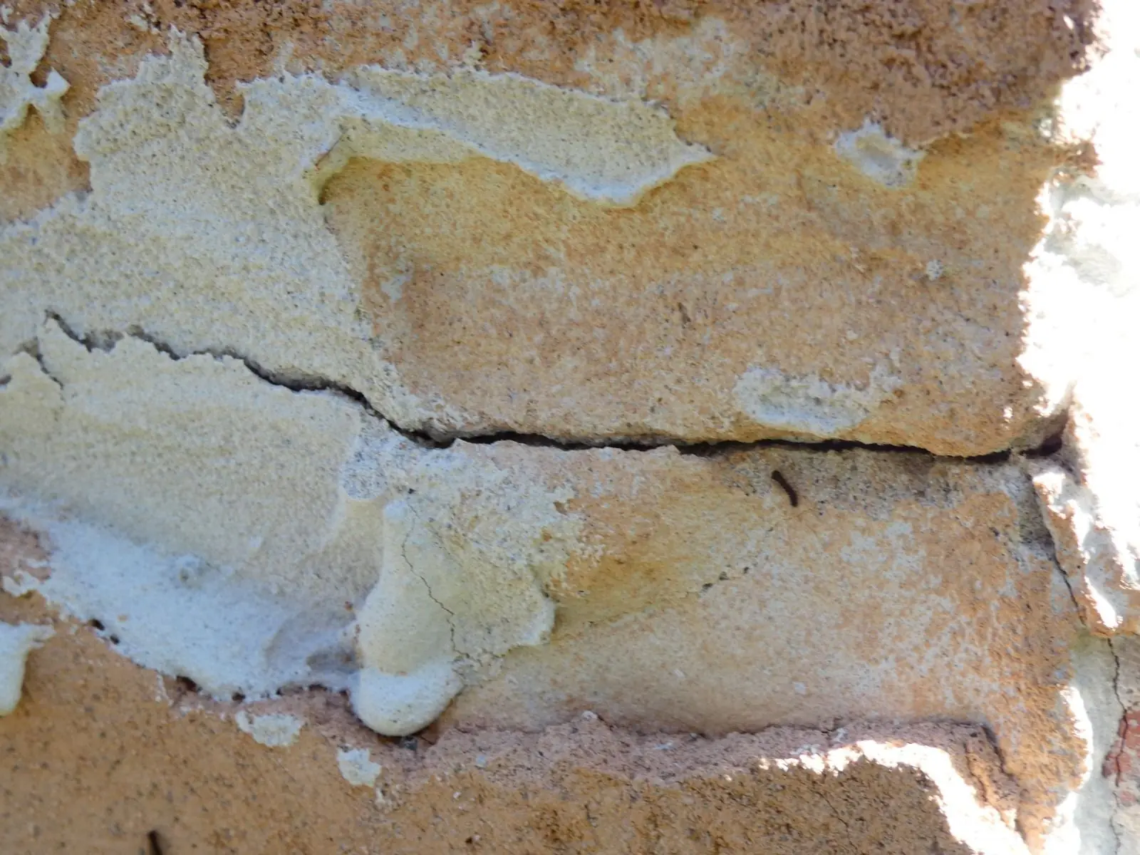 Fissure horizontale dans une maçonnerie à l'enduit décollé